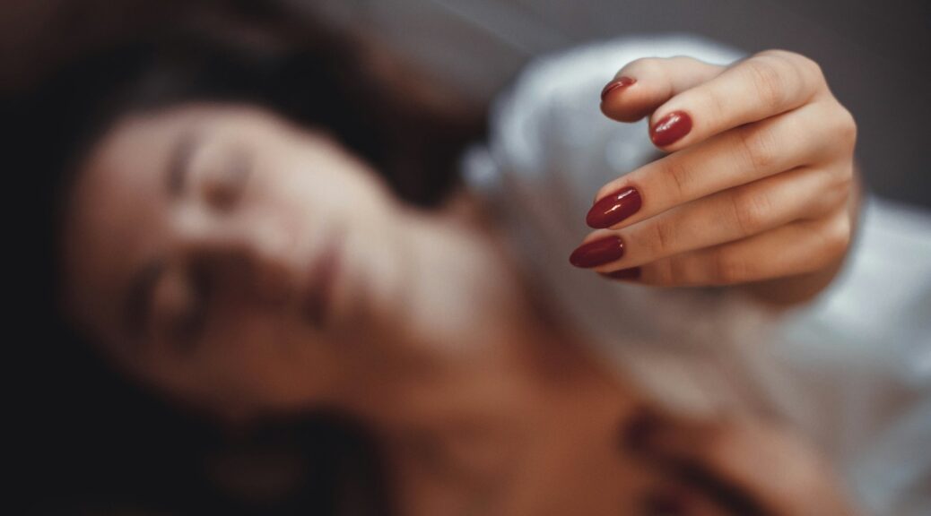 a close up of a woman with a red manicure on her nails