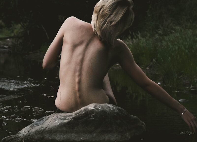 half naked woman sitting on rock