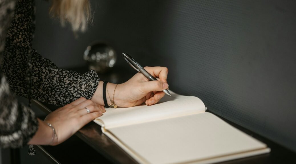 a woman writing on a notebook with a pen