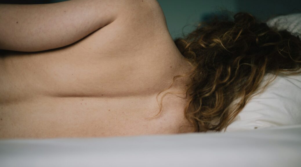 topless woman lying on white bathtub